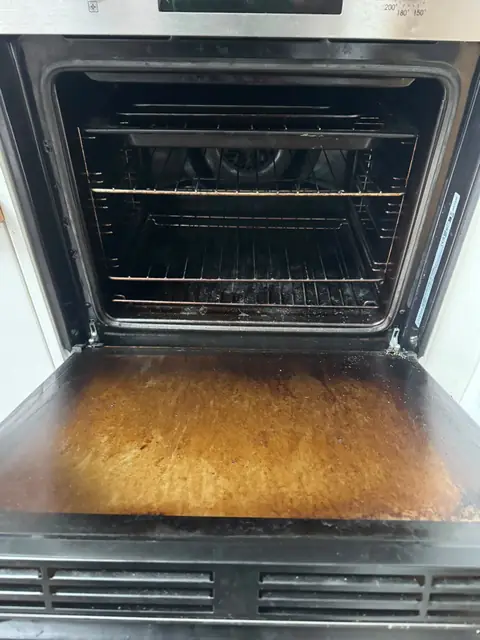 Built-in oven with greasy door and base before cleaning